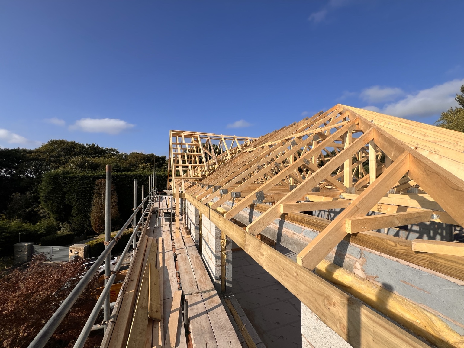 Timber roof trusses under construction above blockwork and scaffolding
